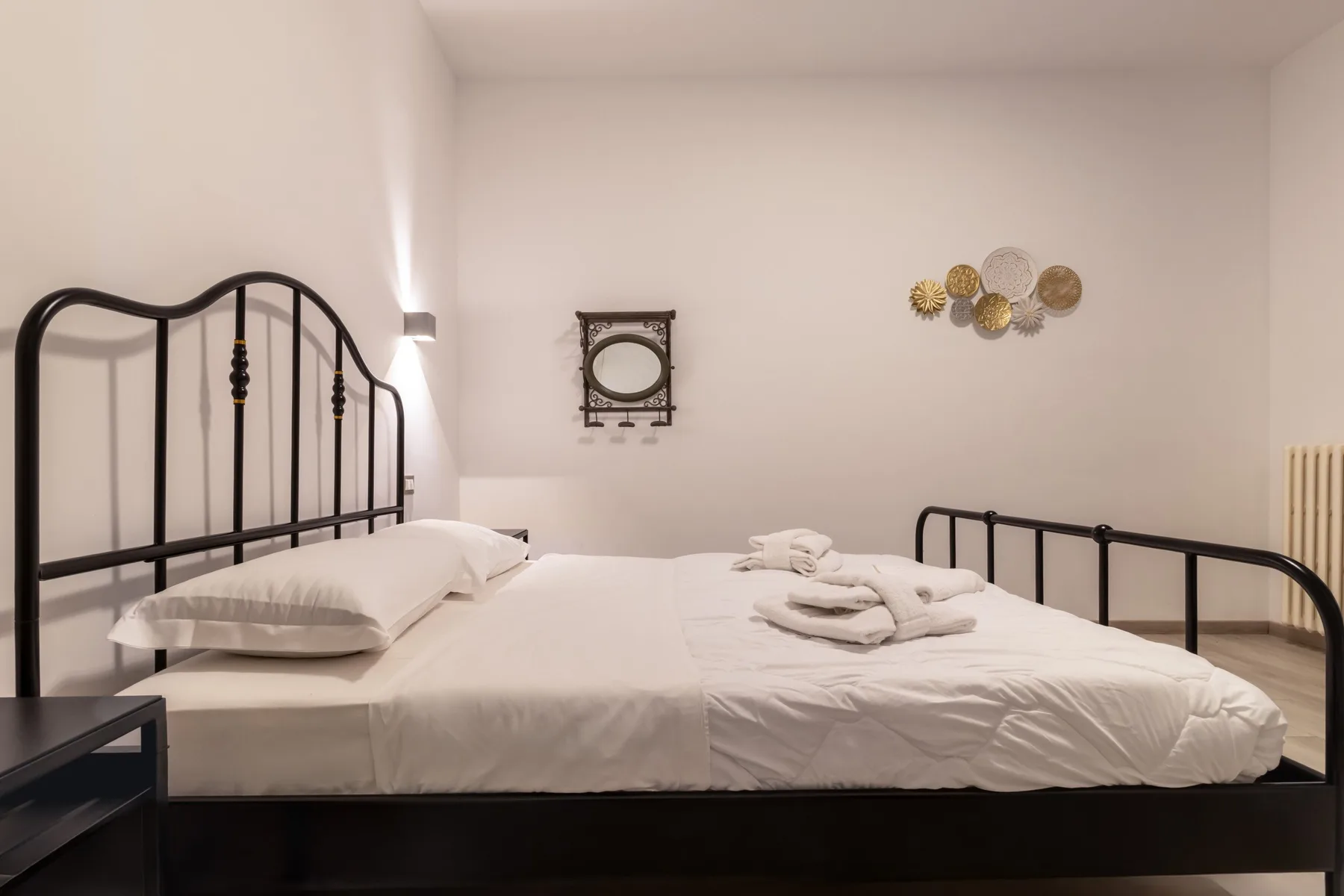 A bedroom with a large bed dressed in white linens and folded towels.