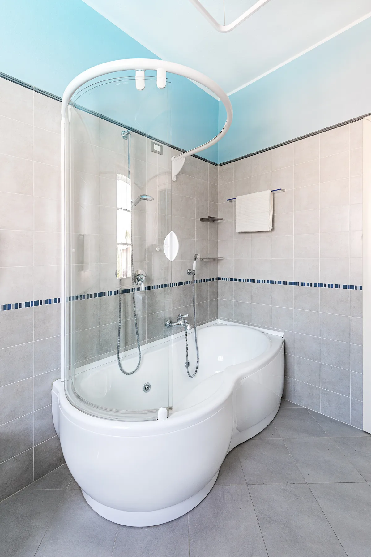 A bathroom with a curved bathtub and glass shower screen.