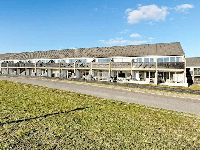 A long modern building with repeated windows stands beside a paved road.