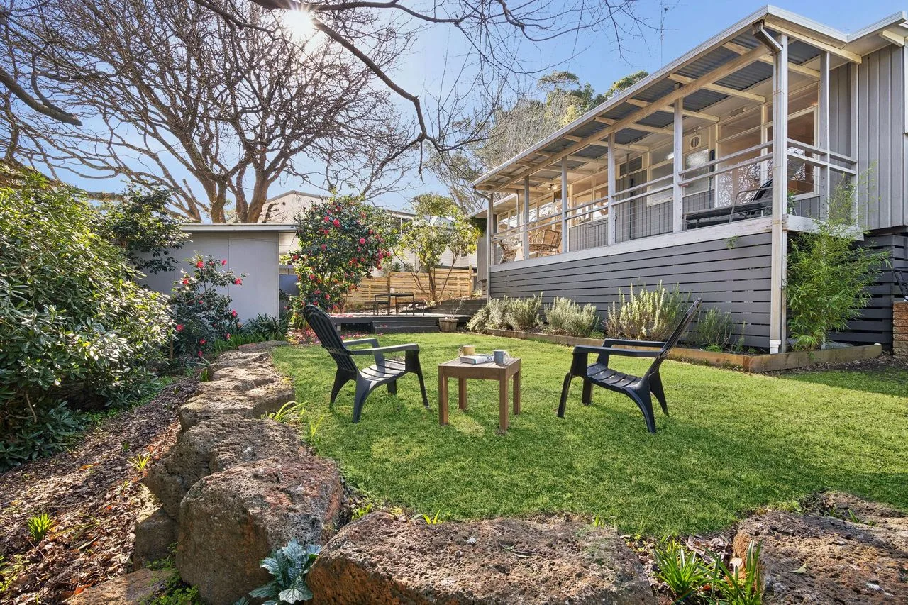 A grassy outdoor seating area beside a raised house.