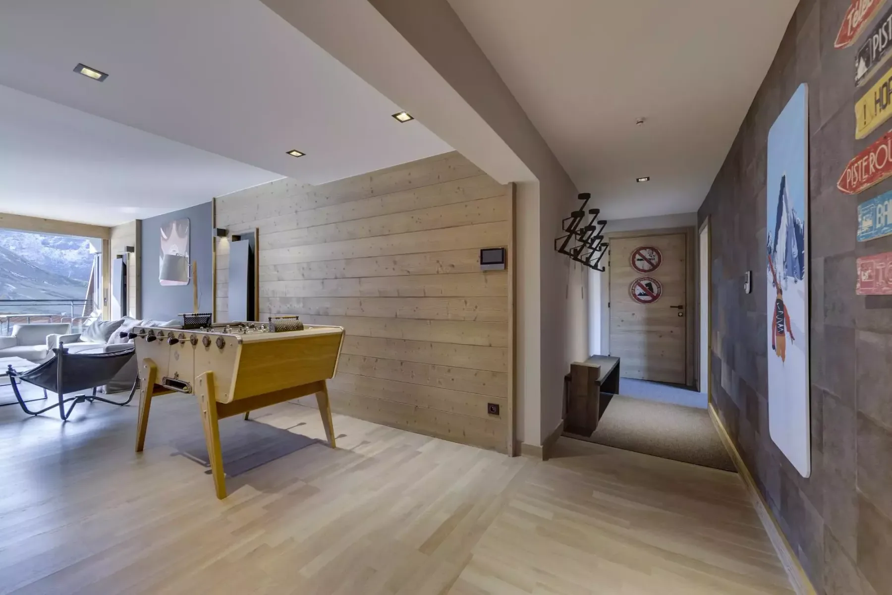 A recreation room with a foosball table, lounge seating, and wall art.