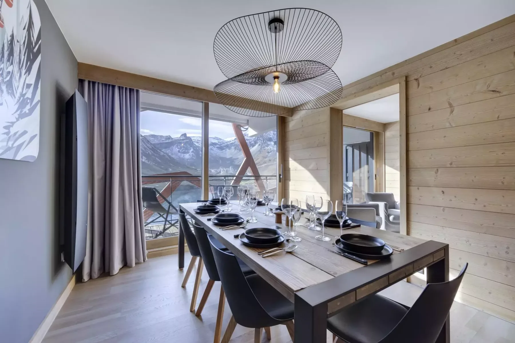 A dining area with a set table beside windows overlooking a mountain view.