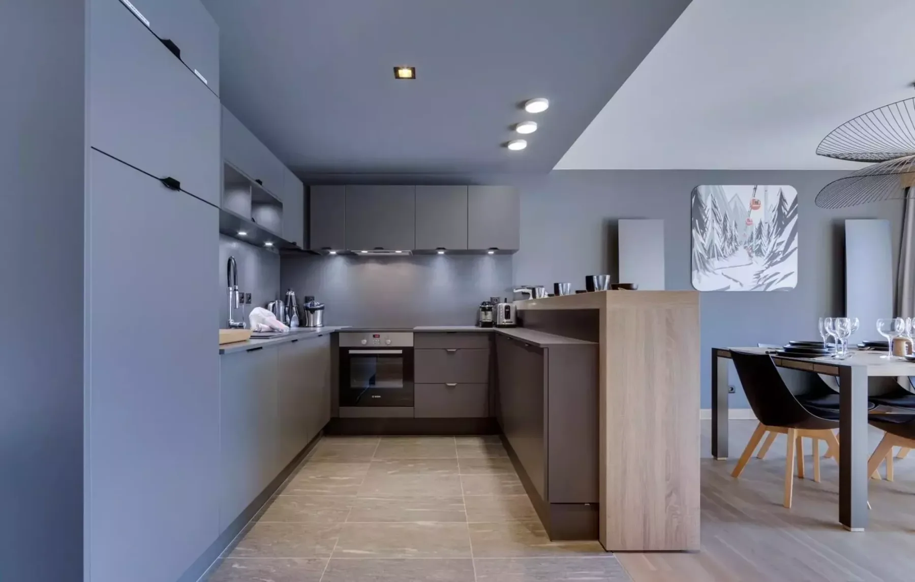 A modern kitchen opens onto a dining area with a table and chairs.