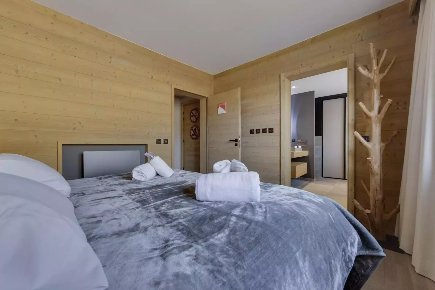 A bedroom with a large bed dressed in gray bedding and white towels.