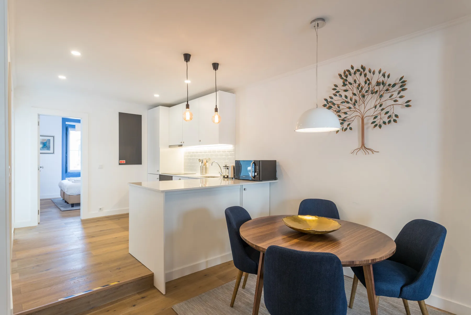 Cocina y comedor de planta abierta con una mesa redonda y asientos azules.