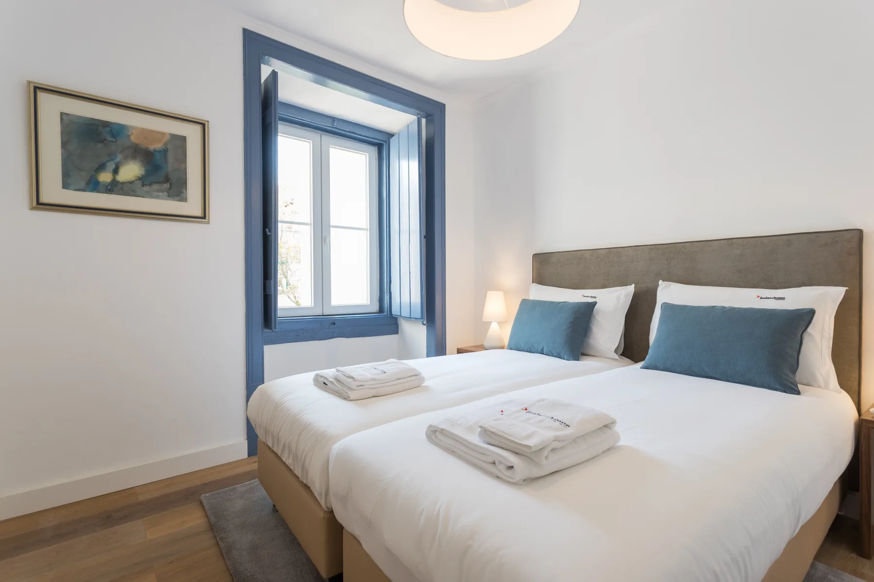 Dormitorio luminoso con una cama amplia y molduras azules en la ventana.