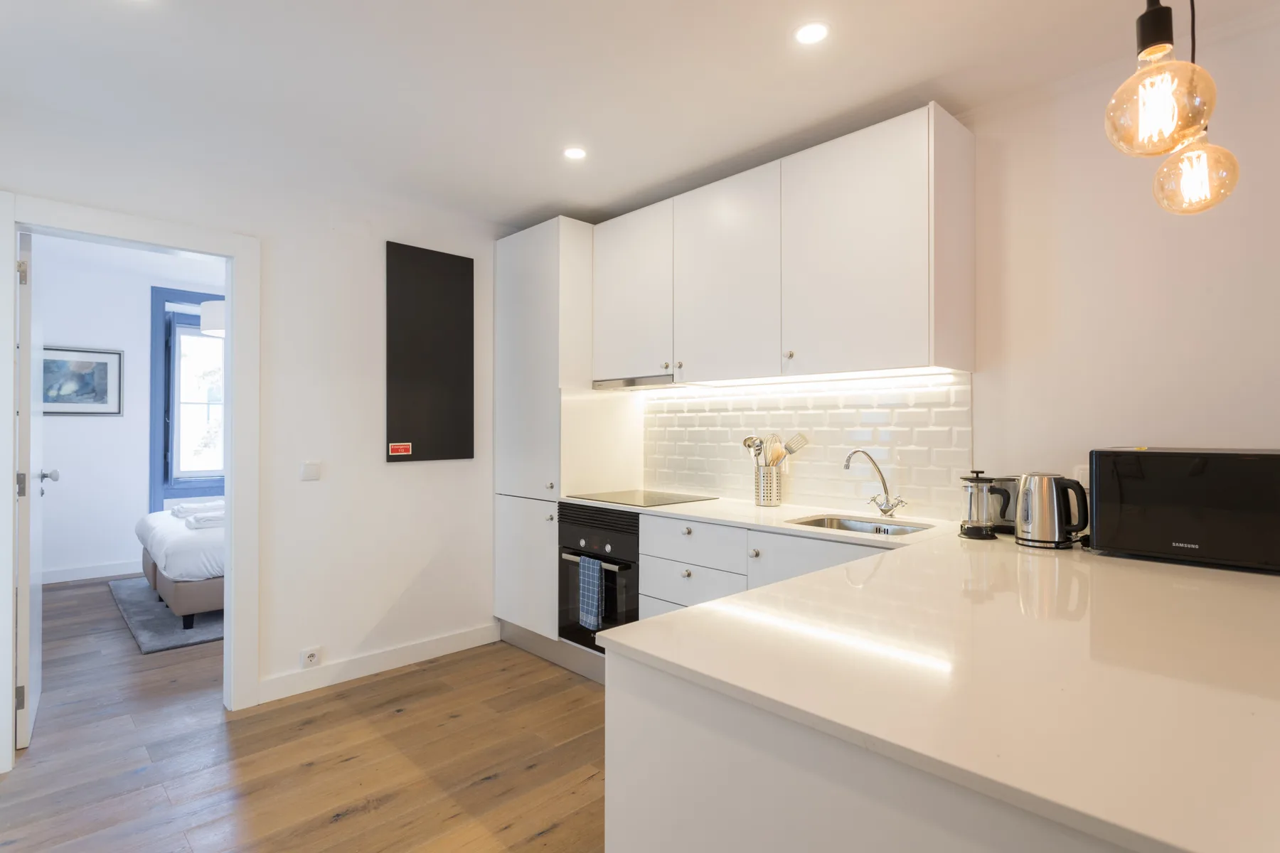 Una cocina moderna y luminosa con gabinetes blancos y una encimera clara.