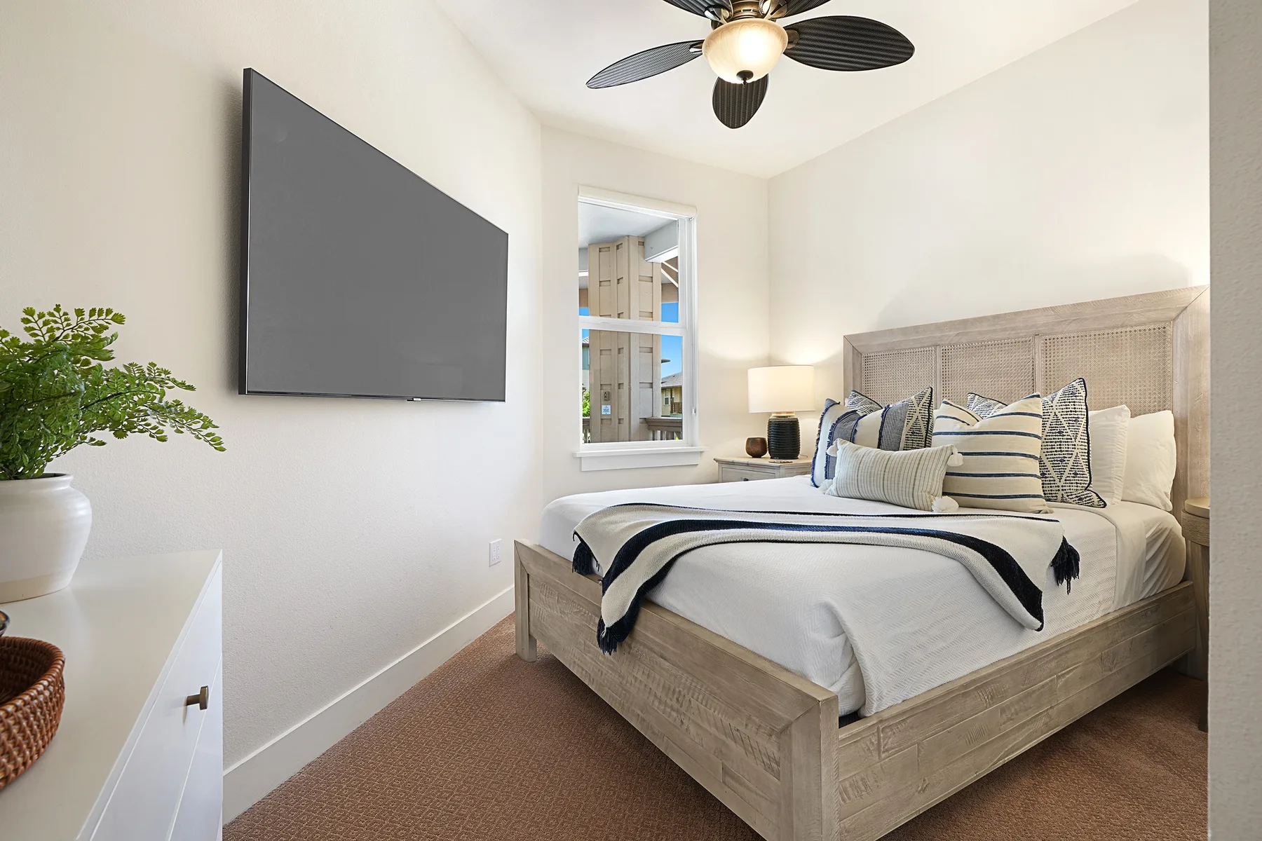 Un dormitorio con una cama bien tendida y una pantalla grande en la pared.