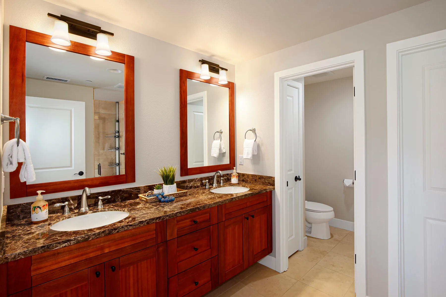 Un tocador de baño con dos lavabos y espejos está junto a una puerta abierta.