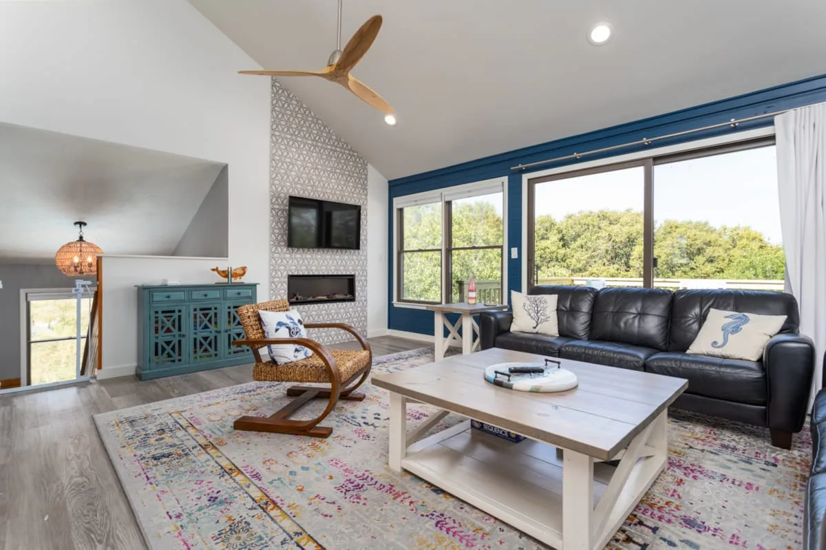 A bright living room with a black sofa, low table, and large windows.