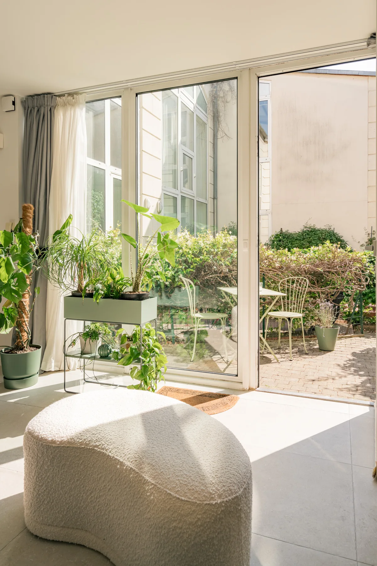 A bright sunroom opens onto a small patio, with plants beside the glass doors.