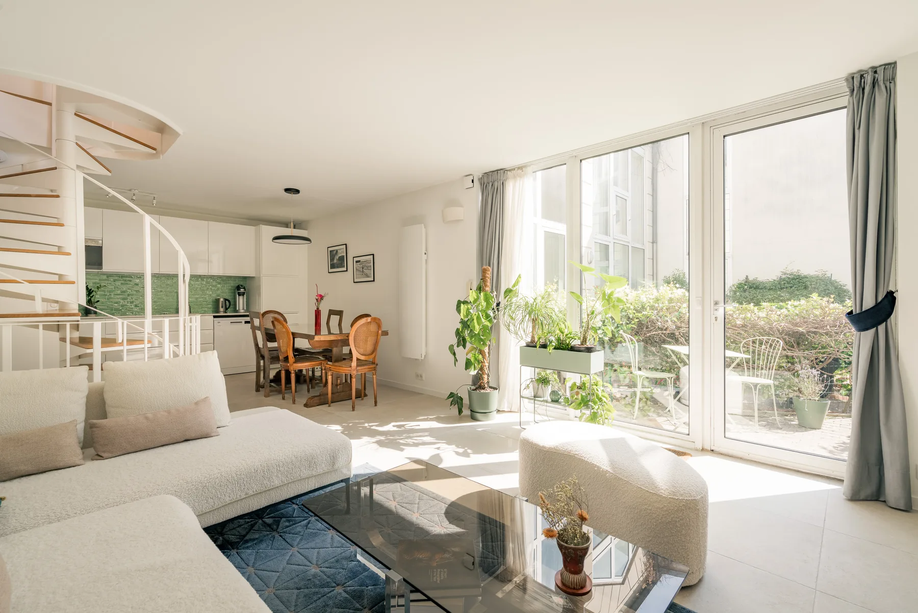 A bright living and dining area with large windows and seating.