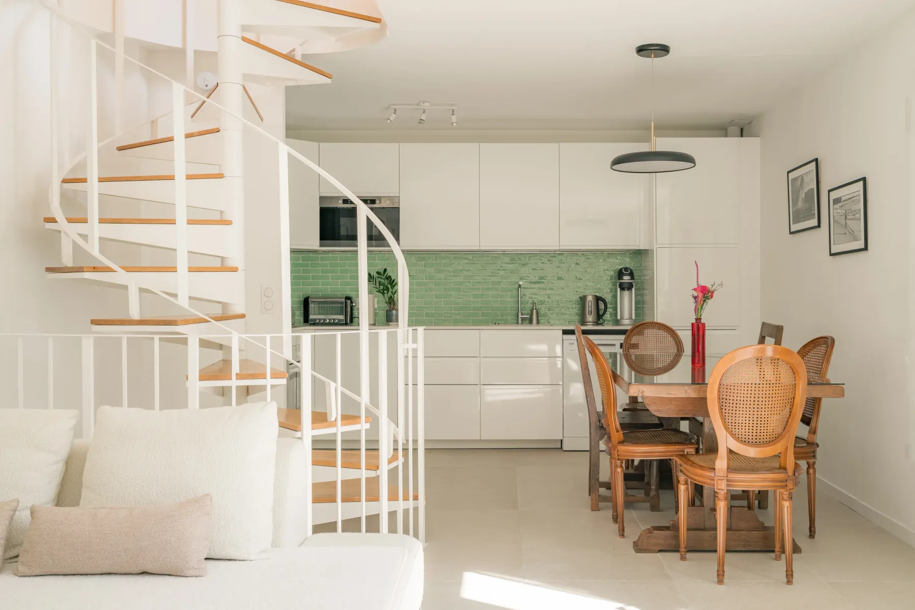 A bright open-plan living and dining area with a kitchen and curved staircase.