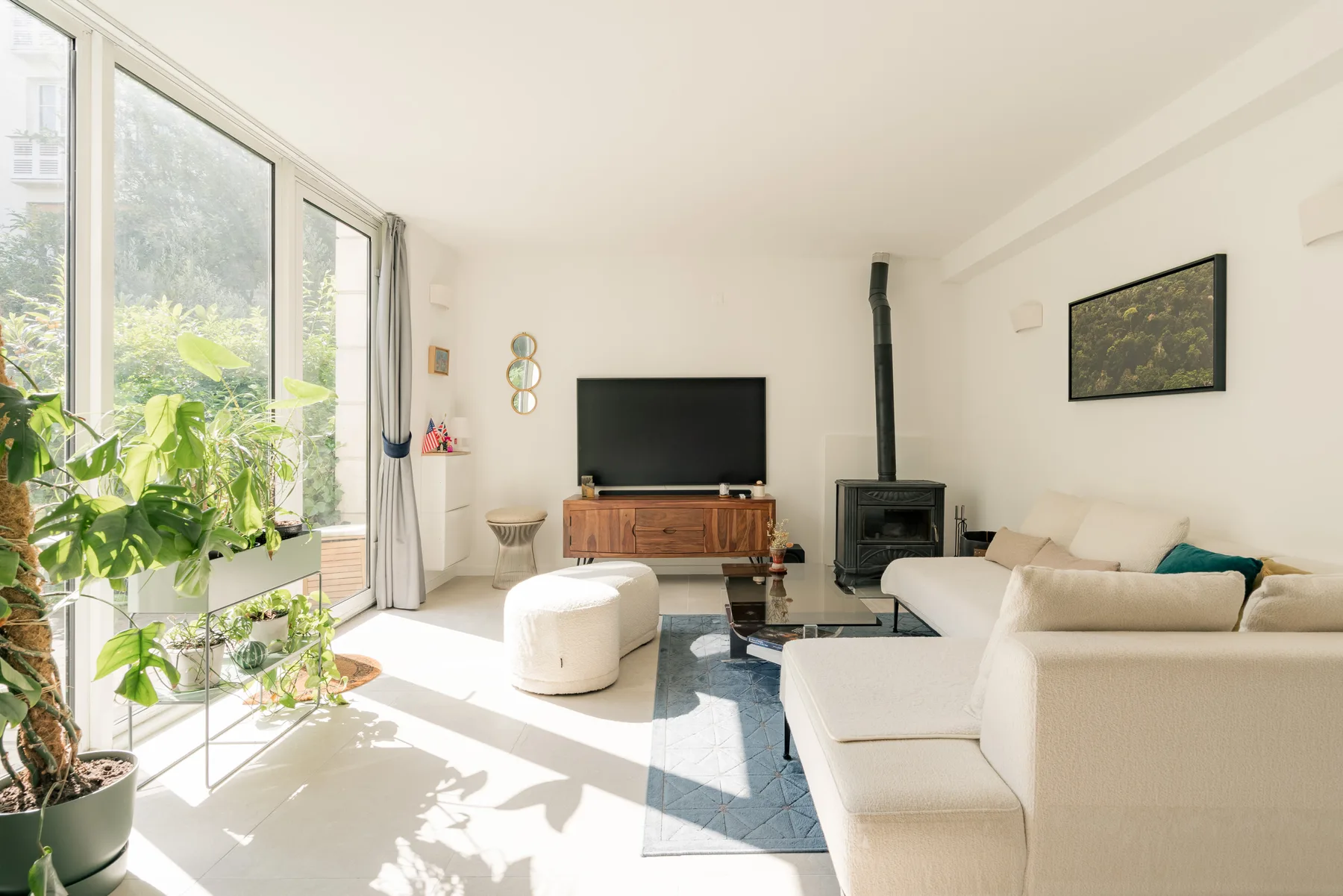 Bright living room with a sectional seating area, television, and large windows.