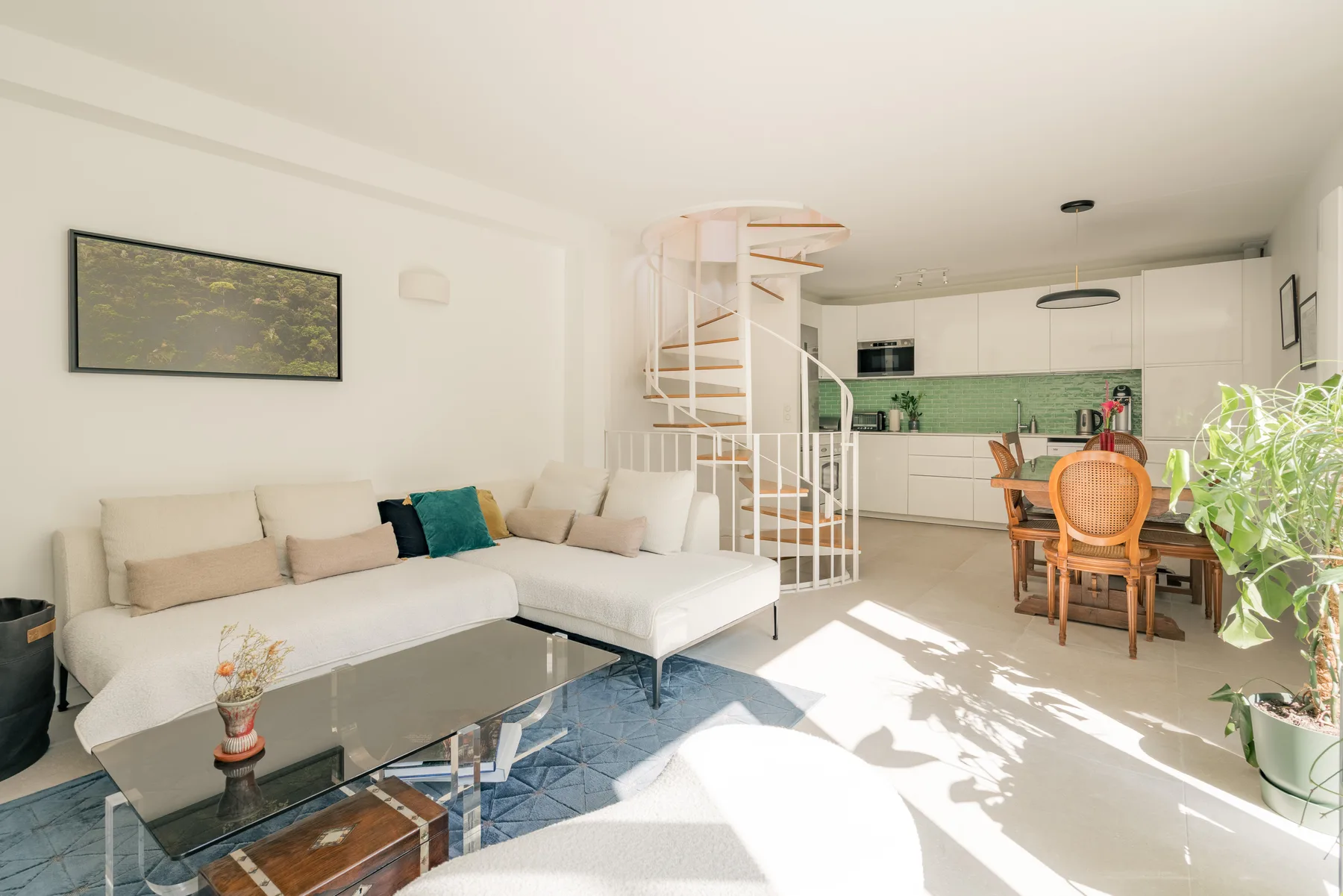 A bright open-plan living and kitchen area with seating and a dining table.