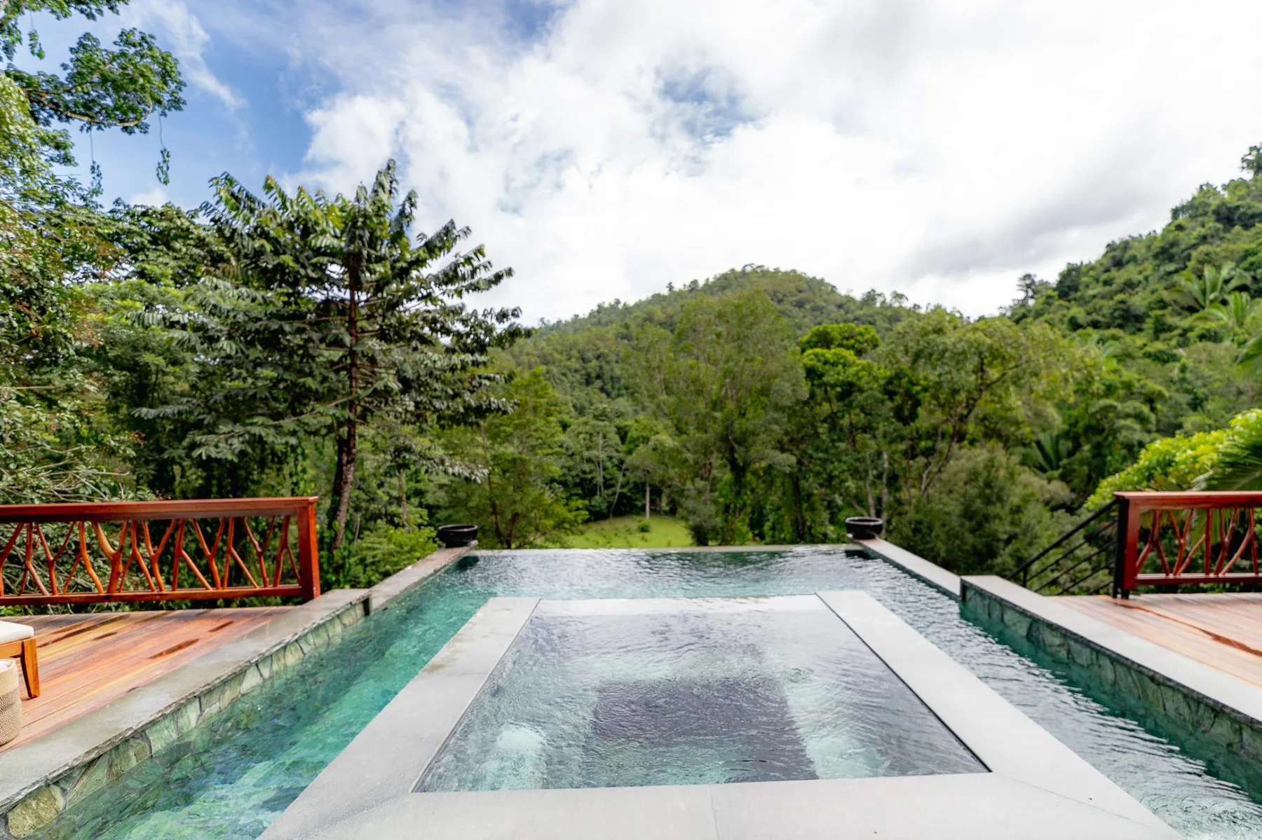 An outdoor pool overlooks a lush, tree-covered hillside.
