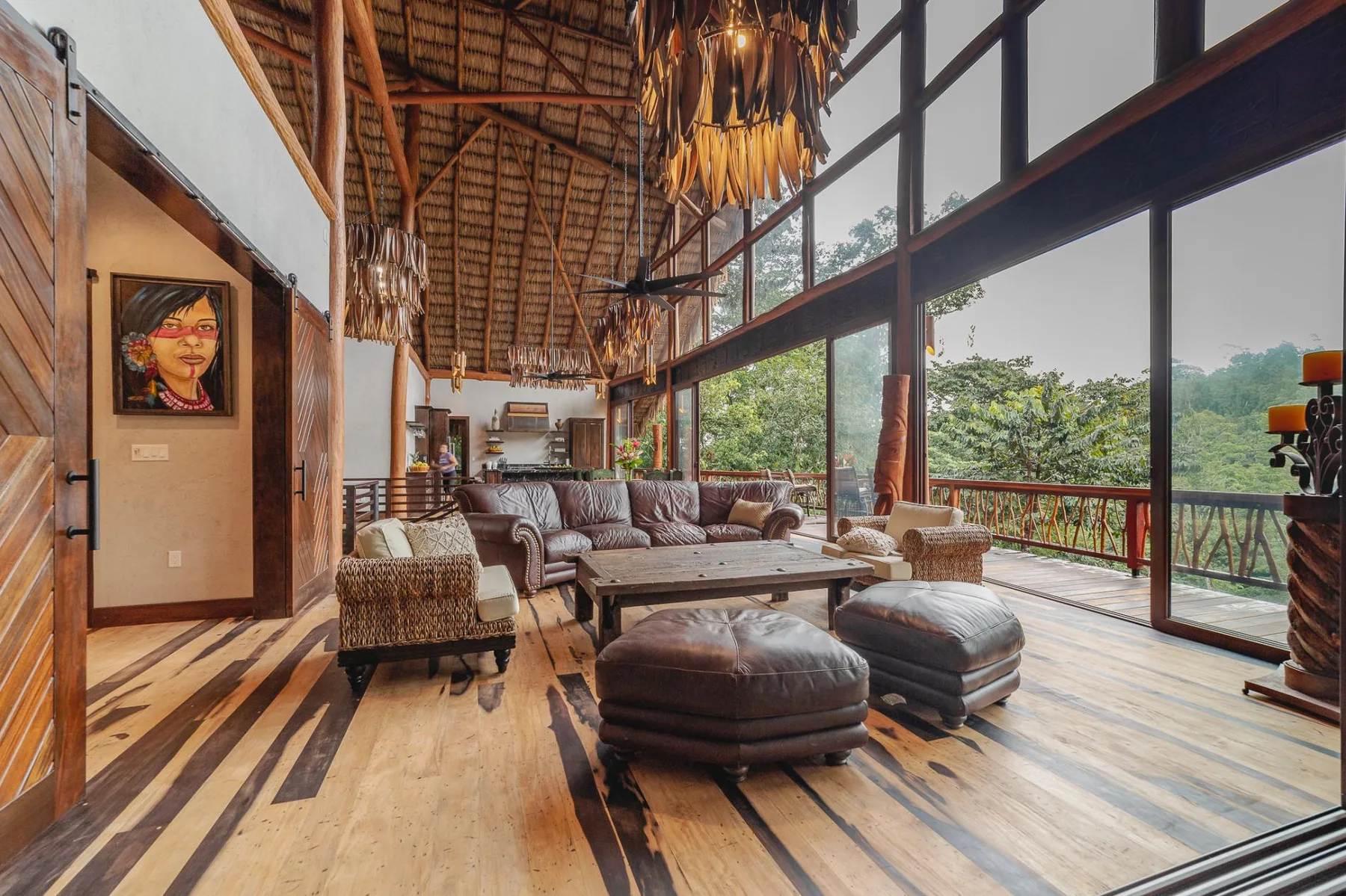 A spacious living room with seating, a low table, and large windows overlooking greenery.