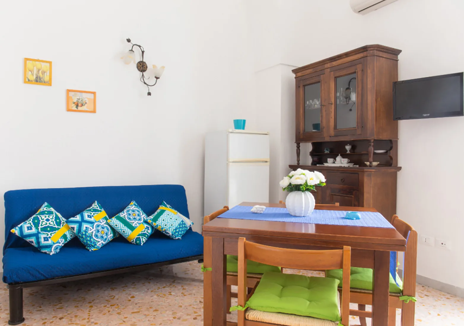 A living and dining area with blue seating and a wooden table.