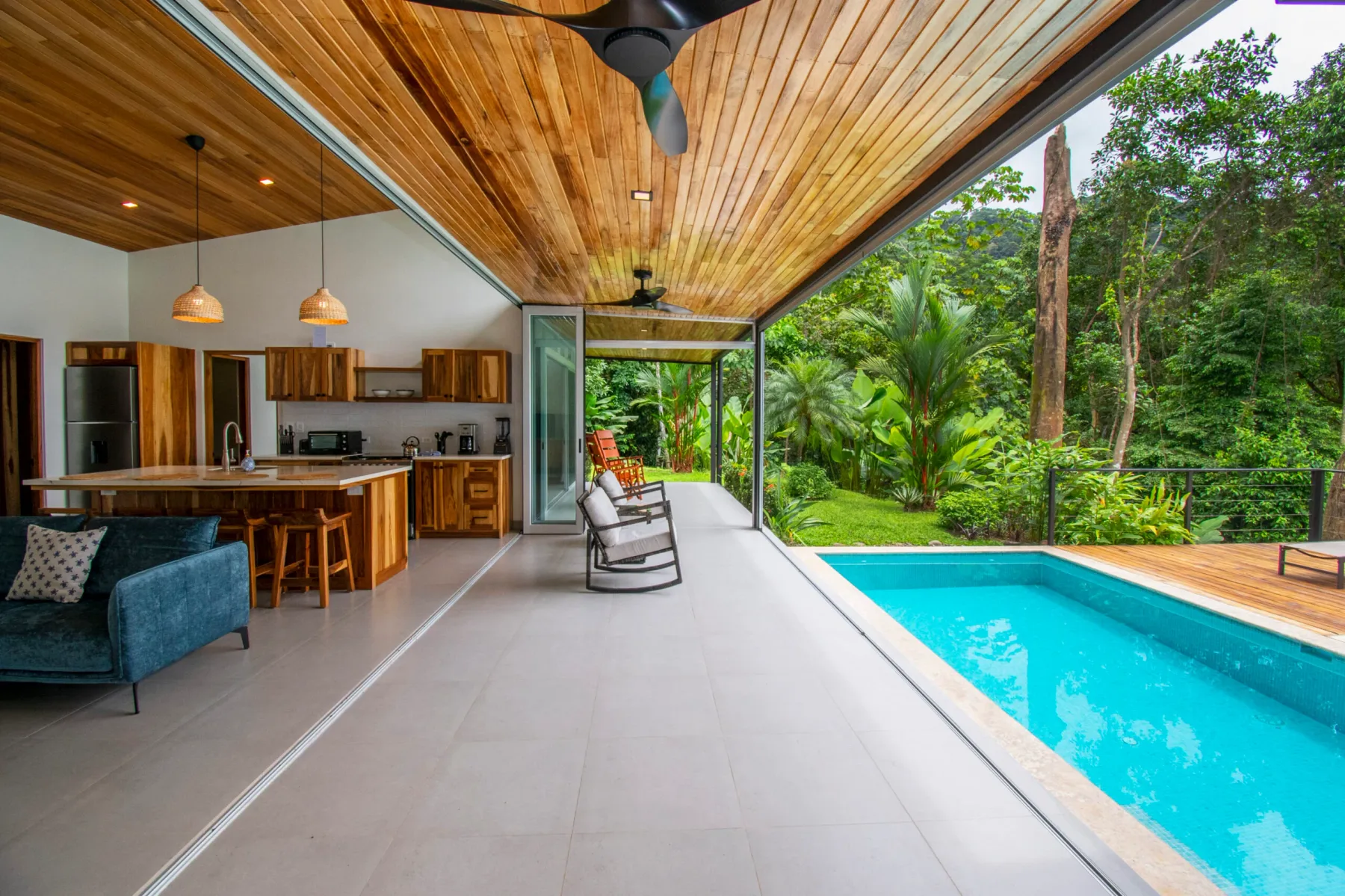 Una cocina y sala de estar de planta abierta dan a un patio junto a una piscina.