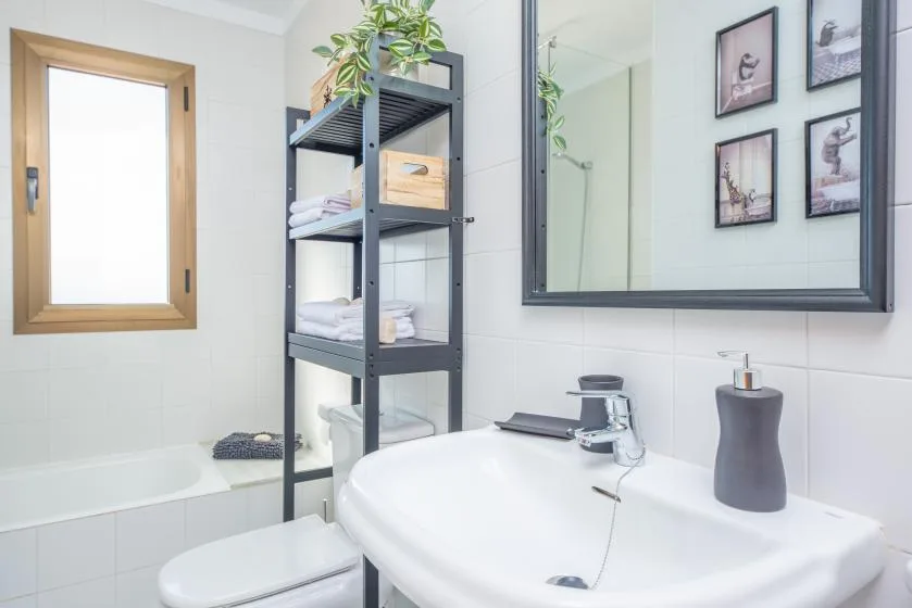 A bright bathroom with a bathtub, sink, and open shelving.
