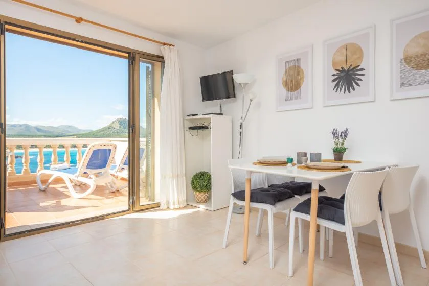 A bright dining area with a table beside an open glass door to a balcony.