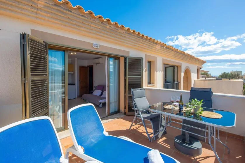 A sunny terrace with blue lounge seating and an open sliding glass door.