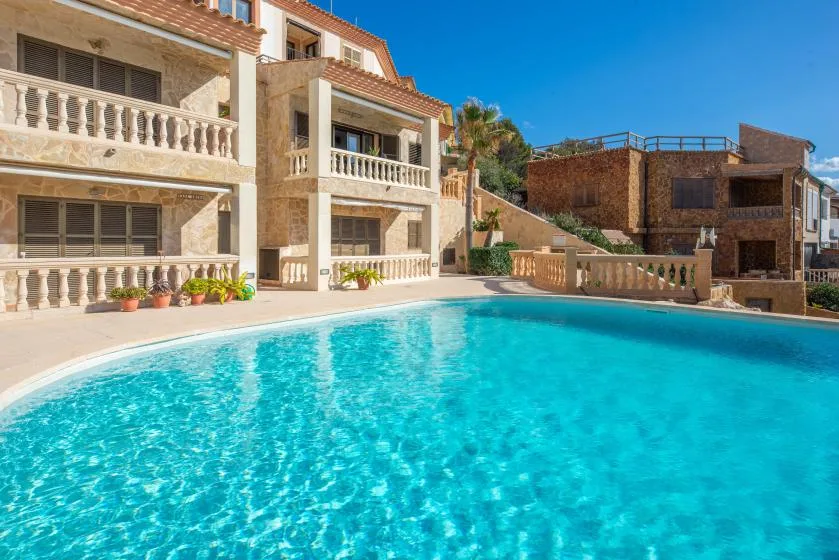 A swimming pool fills the foreground beside a multi-story building.