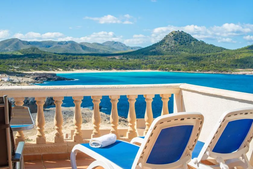A seaside terrace overlooks a sandy beach and blue water.