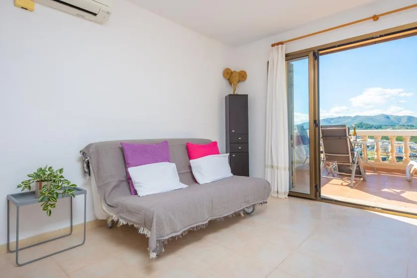 A bright living area with a sofa beside an open balcony door.