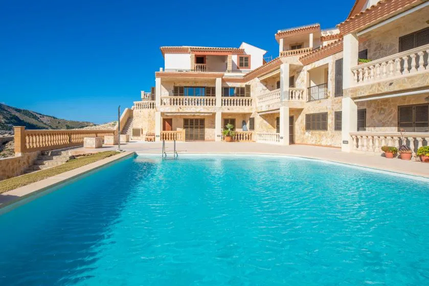 A swimming pool in front of a large building with balconies.