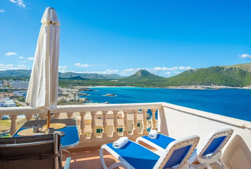 A sea-view terrace with lounge seating and a closed umbrella overlooks the water.