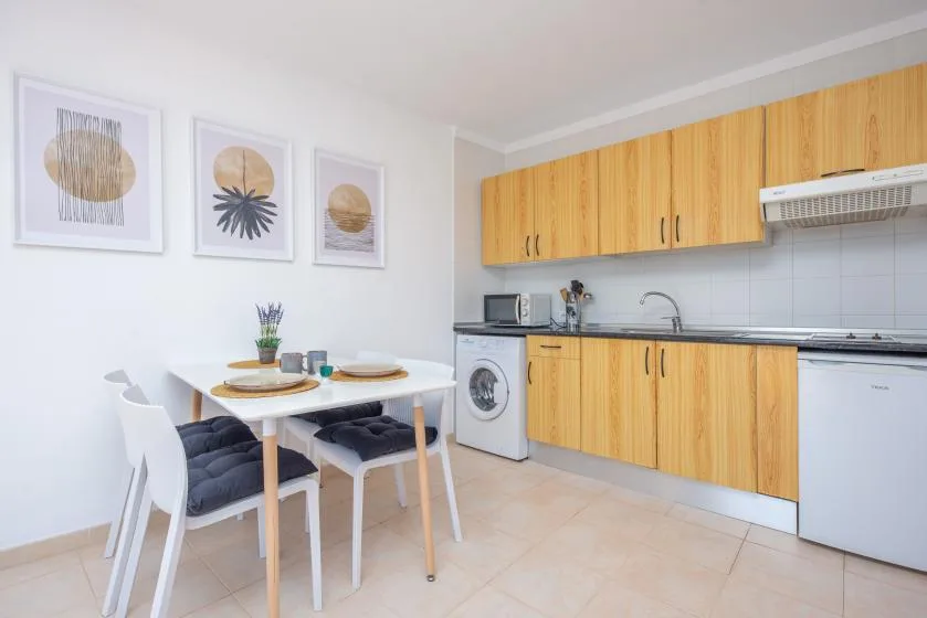 A bright kitchen with wooden cabinets and a small dining table.