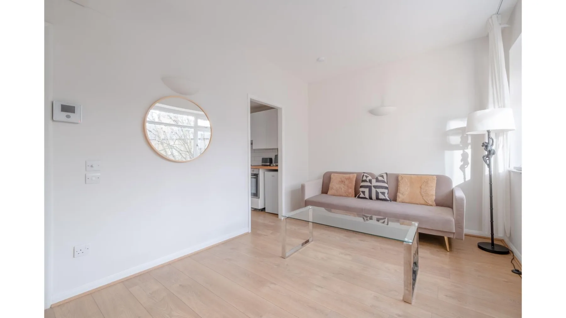 A bright living room with a sofa and glass coffee table.