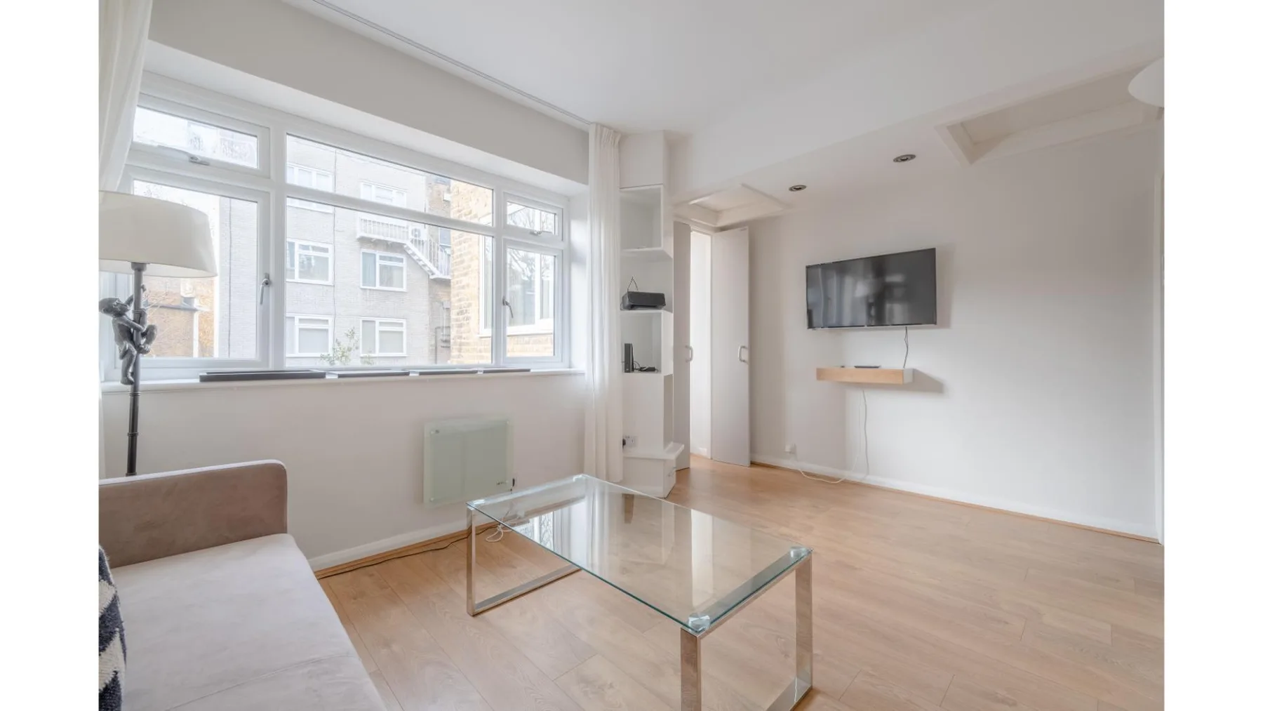A bright living room with large windows and a glass coffee table.