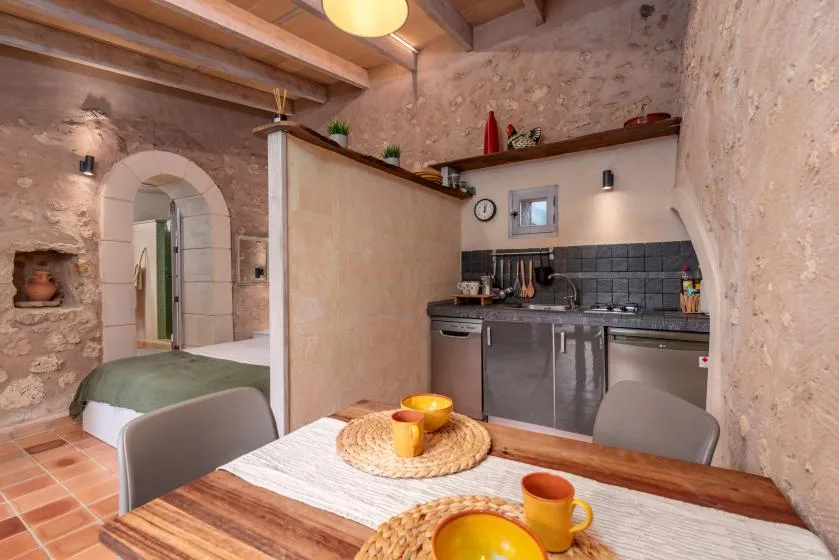 Una cocina rústica con comedor, mesa de madera y vigas expuestas en el techo.