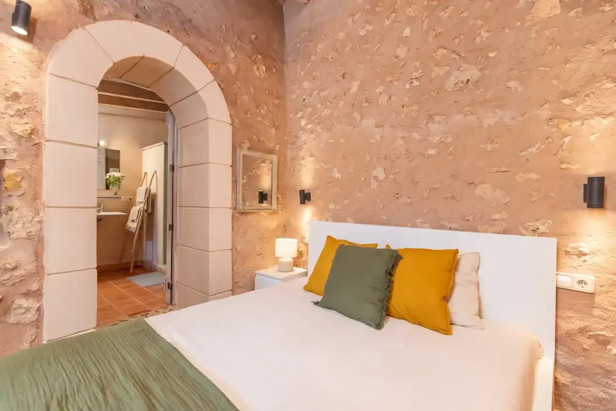A bedroom with a bed and an arched doorway to an adjoining room.