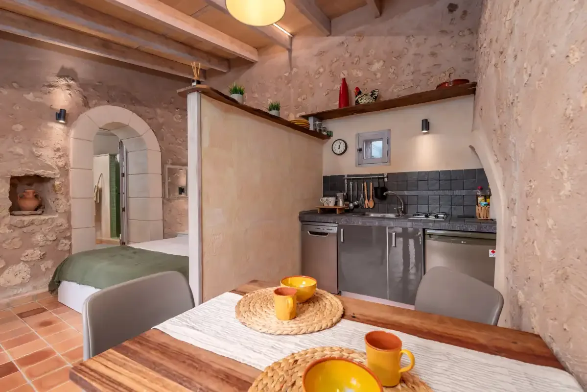 A rustic kitchen and dining area with a table set in the foreground.