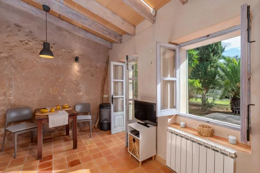 A rustic dining and sitting area with a table beside an open window.