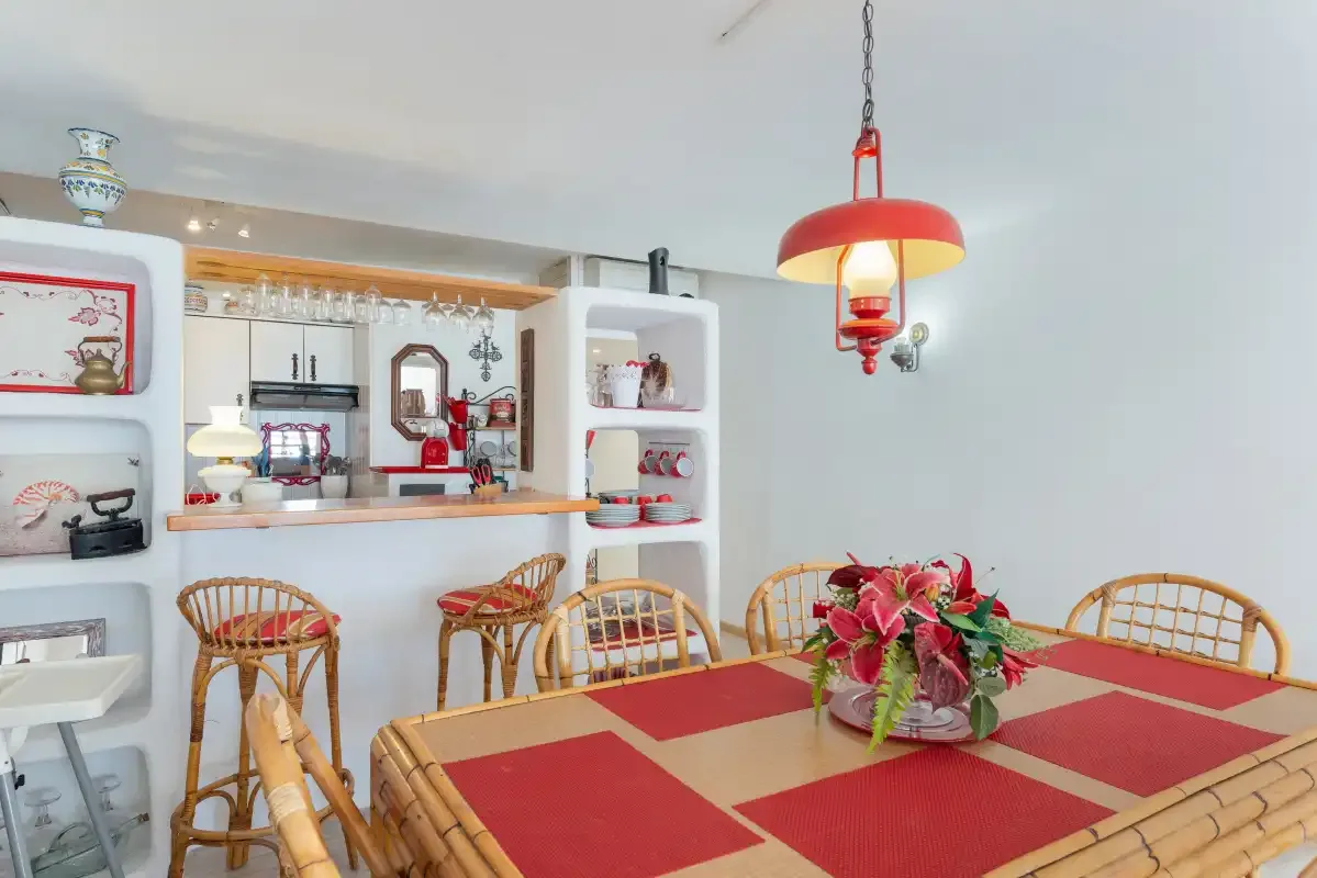 Comedor con un mantel rojo y un arreglo de flores.