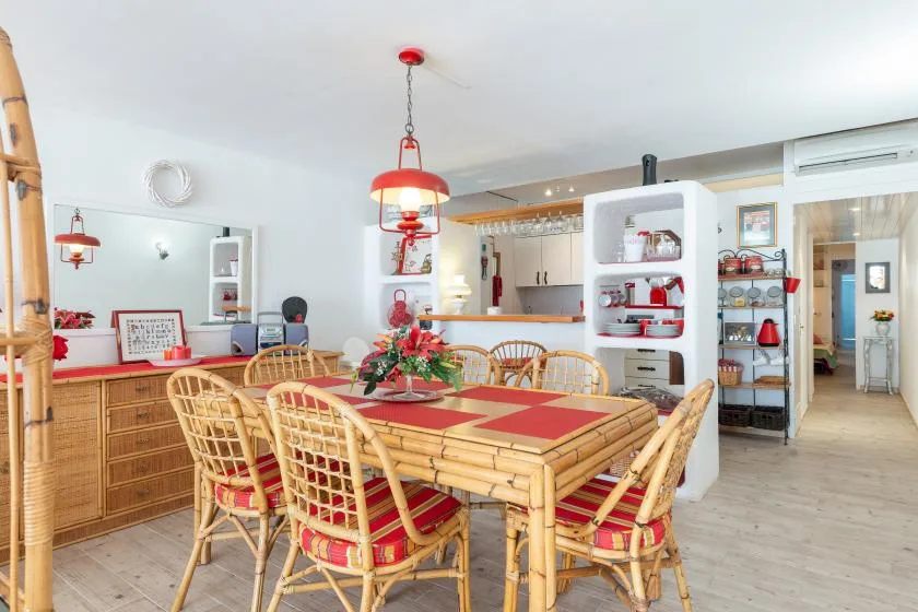 Un comedor con una mesa de bambú y manteles individuales rojos.