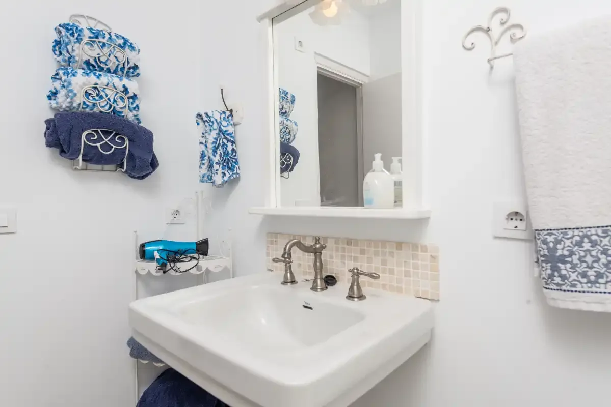 Un lavabo de baño con espejo y toallas estampadas azules.