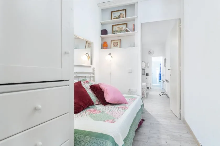 Un dormitorio con una cama bajo estantes de pared y una puerta abierta.