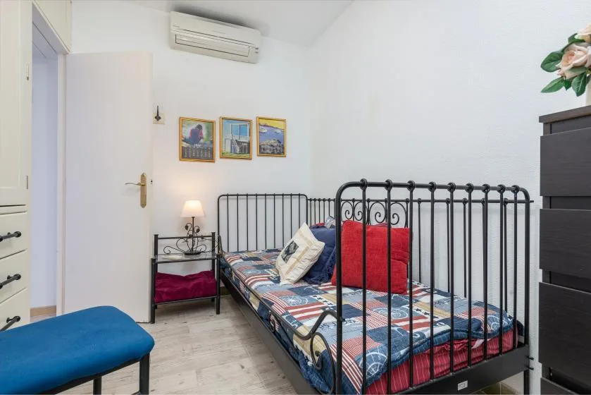 Un dormitorio con una cama de metal negro, ropa de cama colorida y cuadros en la pared.