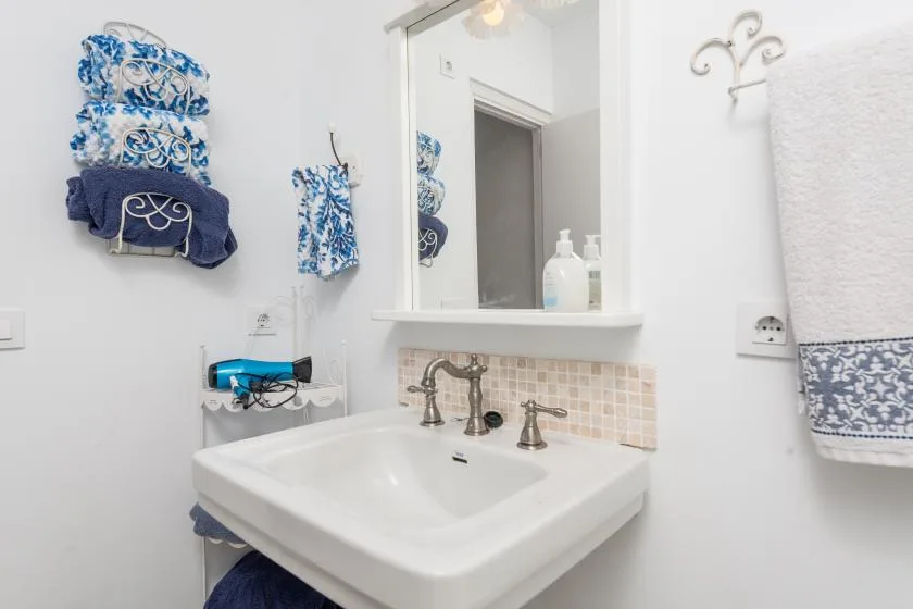 Un lavabo de baño está bajo un espejo, con toallas estampadas colgadas cerca.