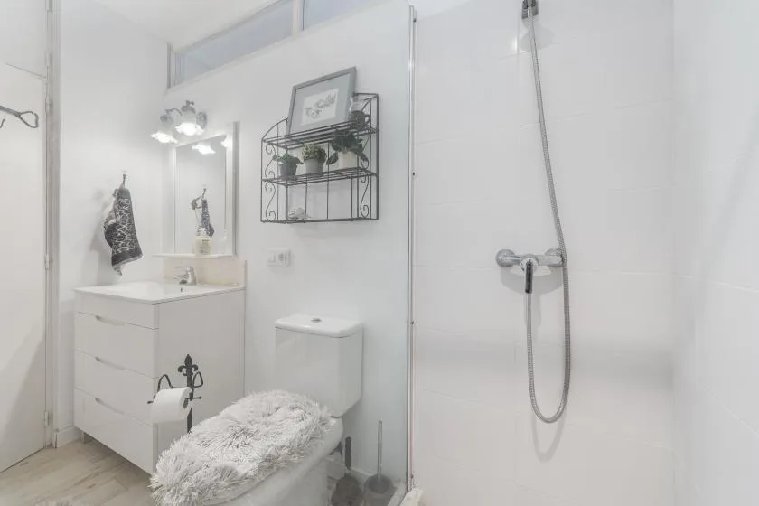 Un baño luminoso con un tocador y una ducha.