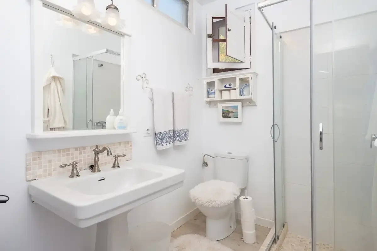 Un baño luminoso con lavabo, inodoro y ducha.