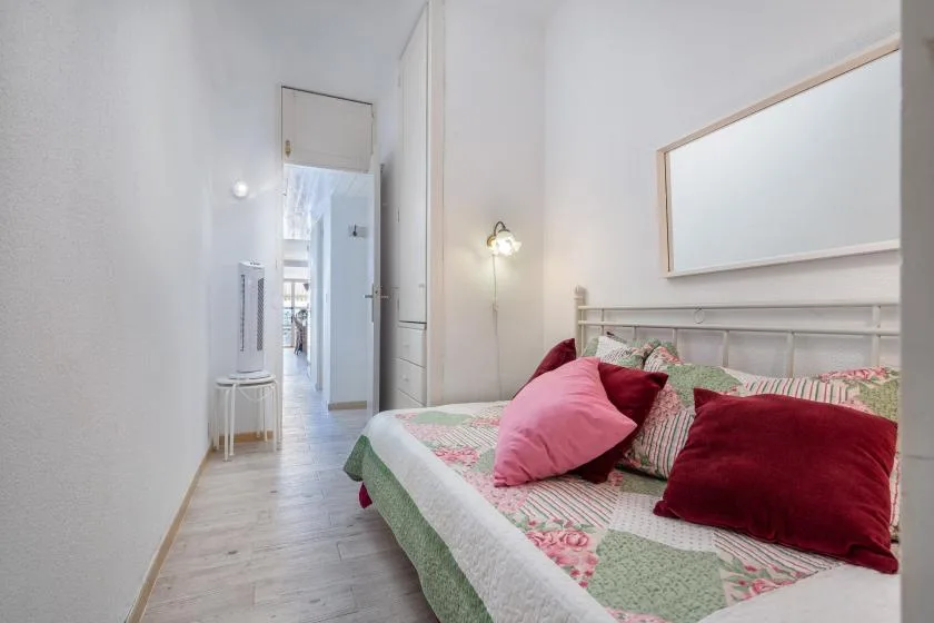 Un dormitorio con una cama vestida con ropa de cama floral y cojines de colores.