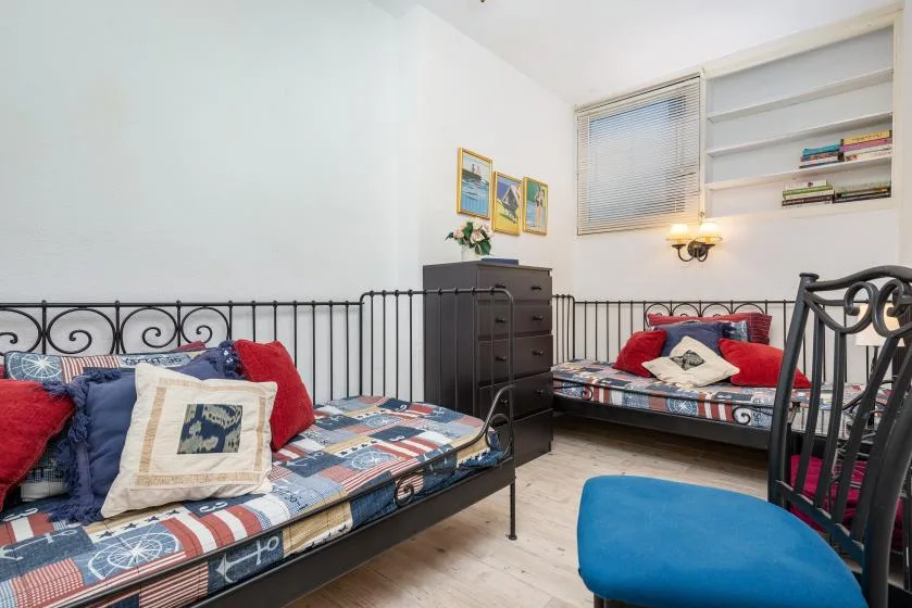 Un dormitorio con dos camas, ropa de cama colorida y estantes empotrados.