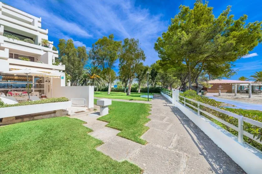 Un camino pavimentado atraviesa una zona ajardinada al aire libre junto a un edificio blanco.