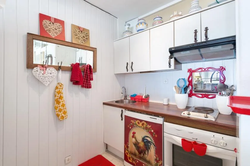 Una cocina pequeña con gabinetes blancos, encimera de madera y estufa.